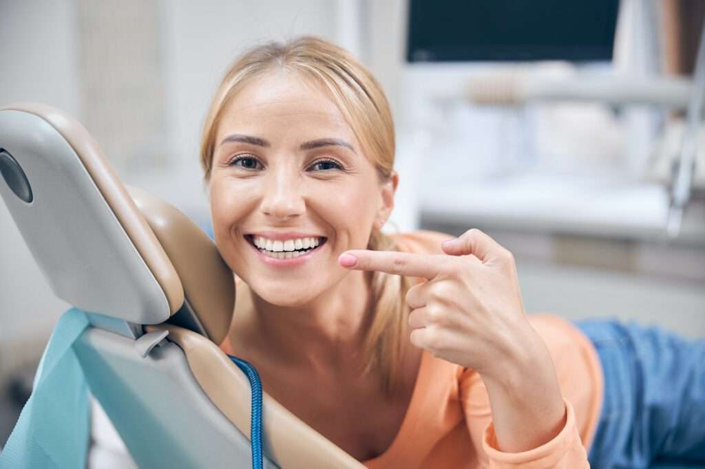 Merry young woman demonstrating perfect smile in clinic